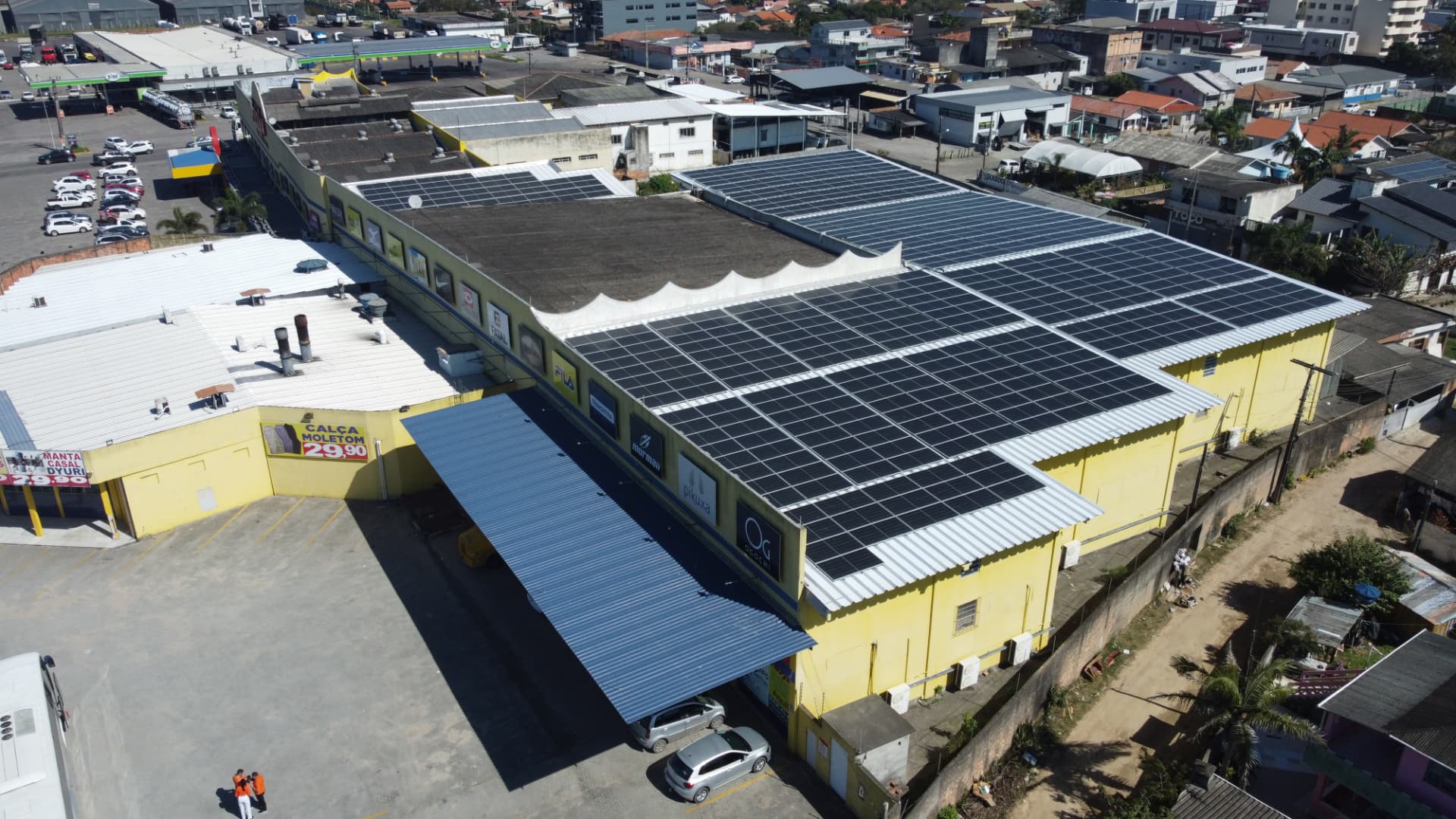 Vista aérea do telhado comercial da Ferju com múltiplos arranjos de módulos fotovoltaicos sobre a loja