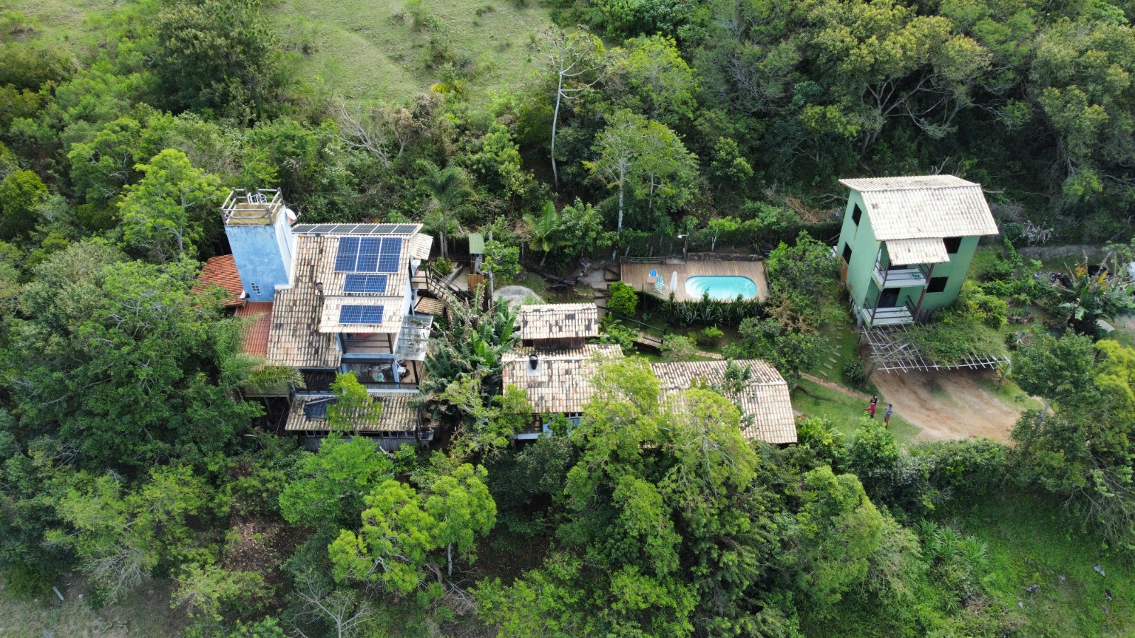 Vista aérea do Projeto 08 — complexo rural cercado de mata, com módulos fotovoltaicos instalados sobre os telhados